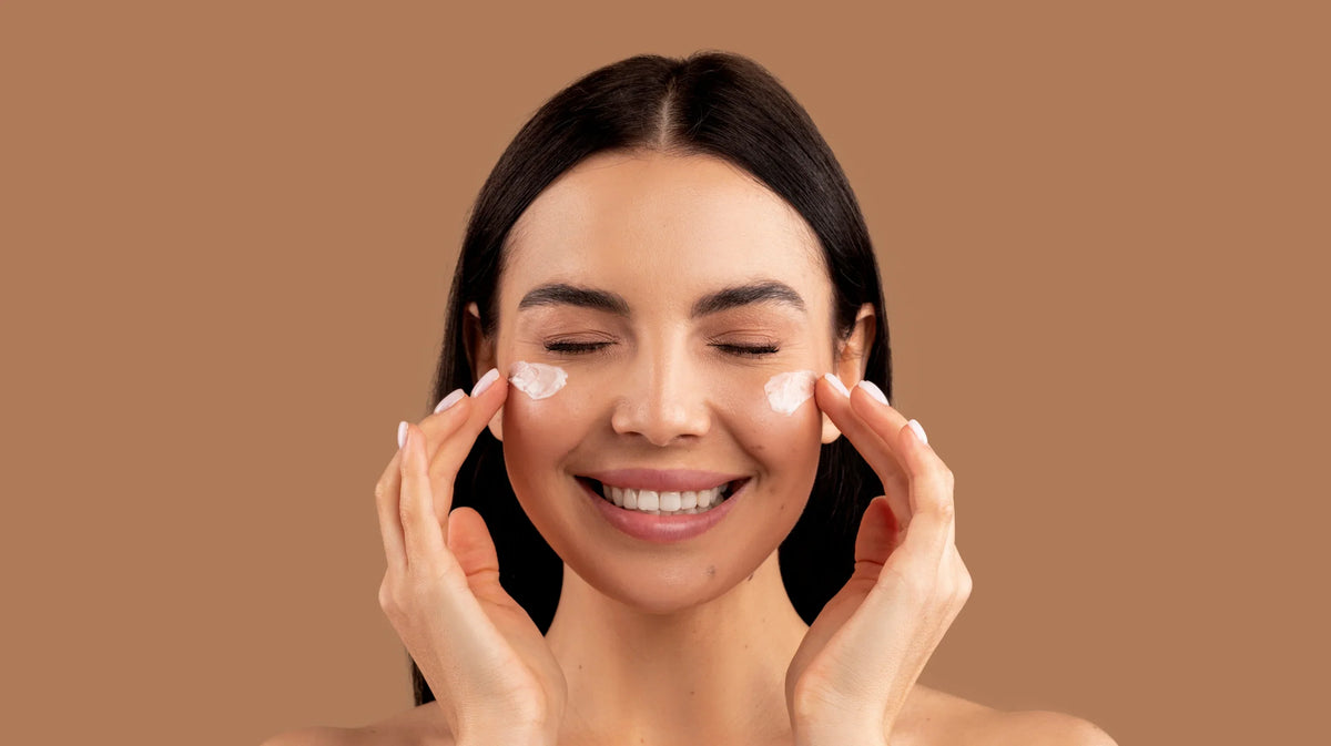 Femme souriante appliquant une crème sur ses joues