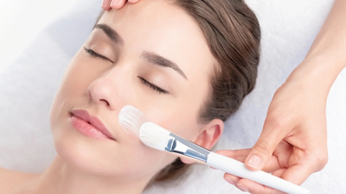 Application d’un masque au pinceau sur le visage en institut